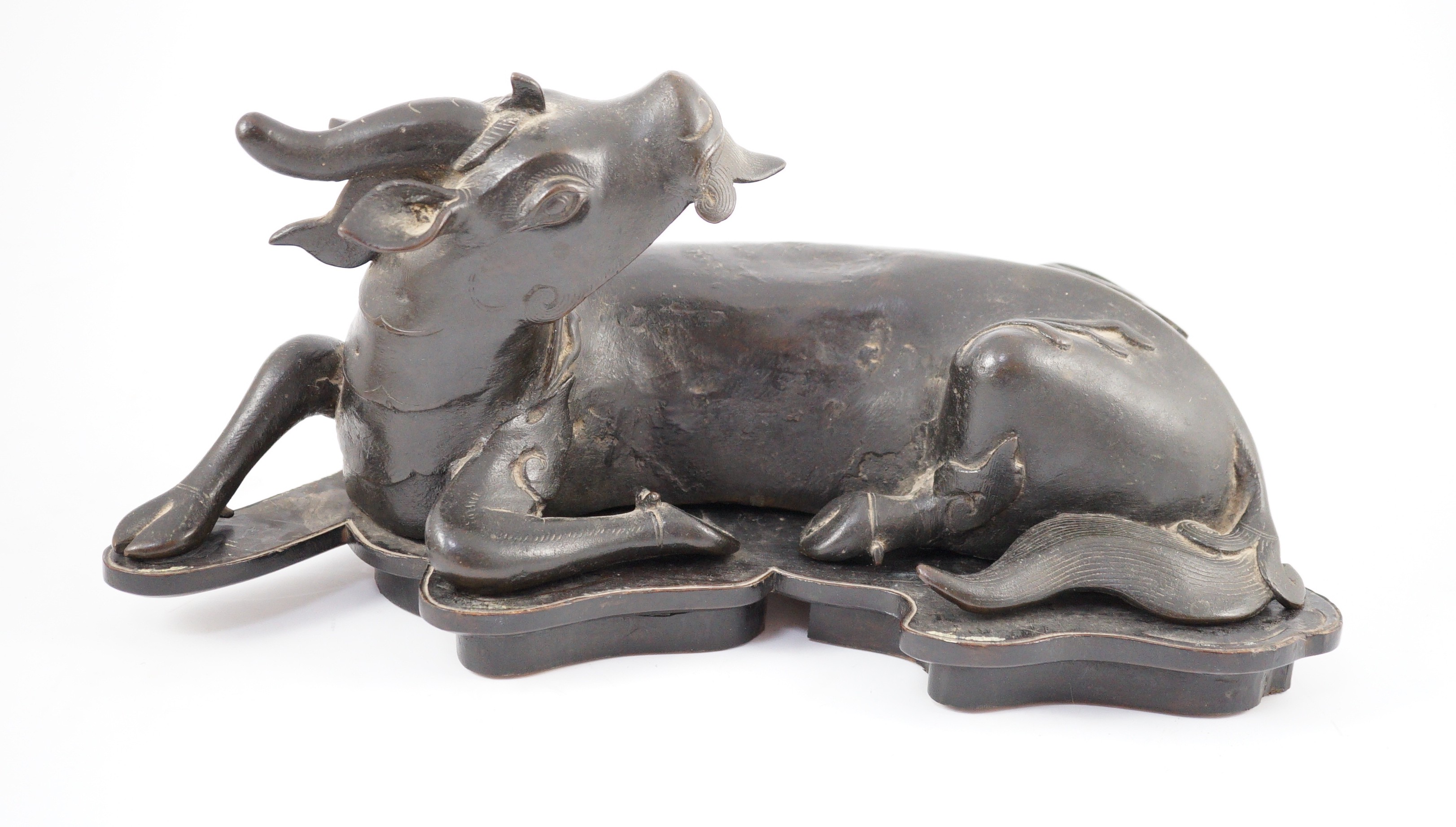 A Chinese bronze figure of a recumbent qilin, late Ming dynasty, 36cm long, old repairs and later base panel, wood stand